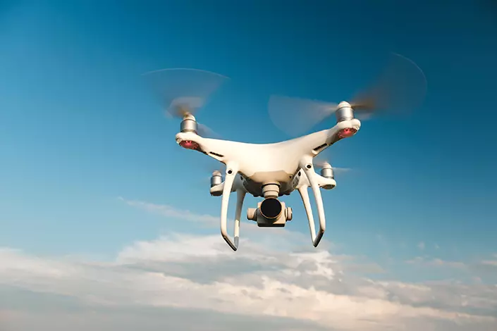 Drone bianco in hovering sfondo cielo blu